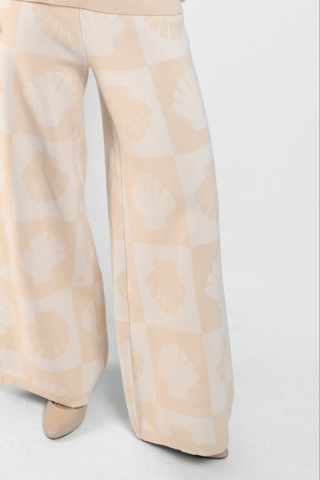 Beige and cream knit wide-leg trousers with a shell pattern.