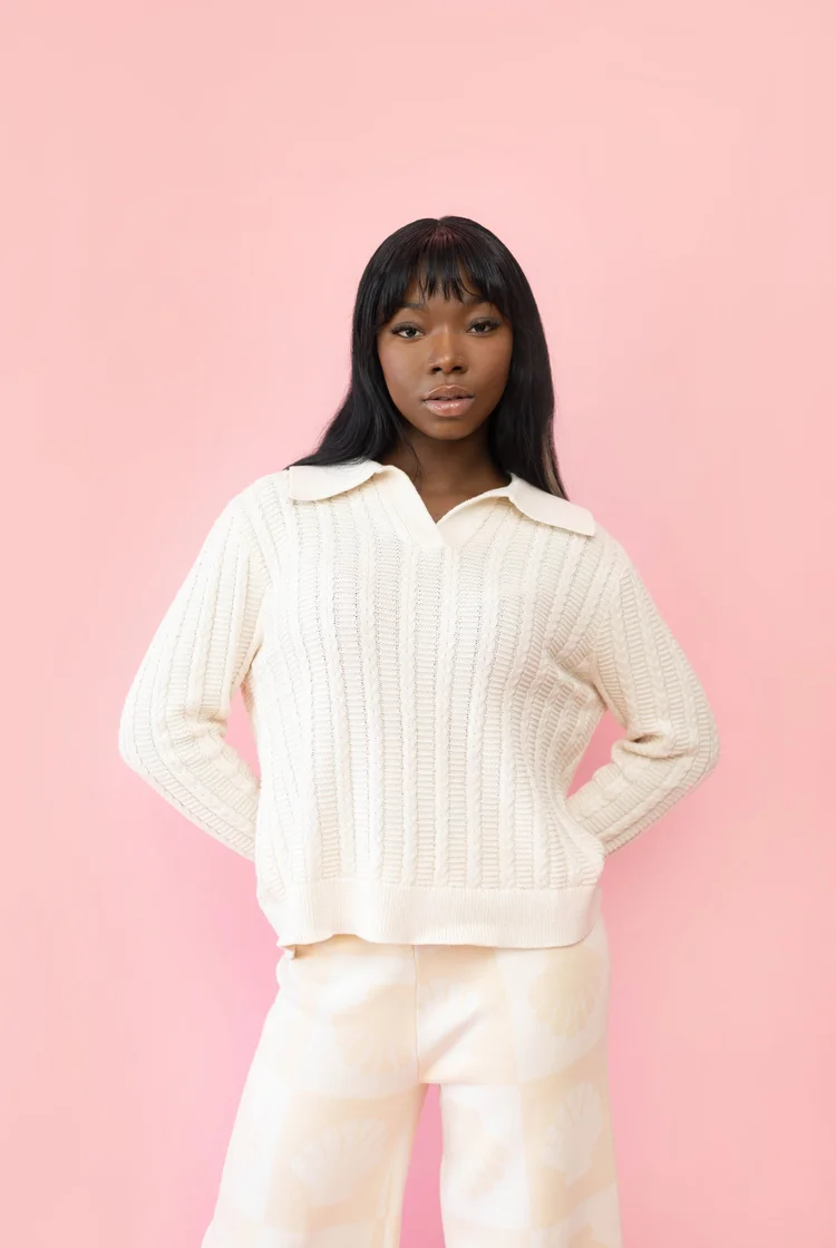 Woman wearing a ribbed cable knit sweater with polo collar. 