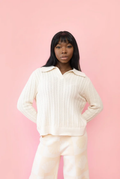 Woman wearing a ribbed cable knit sweater with polo collar. 