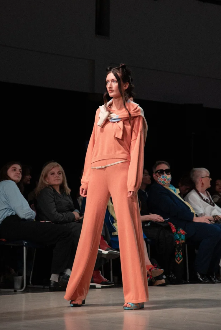 Model wearing a coral coloured knit wide-leg lounge pants with the matching knit crewneck.