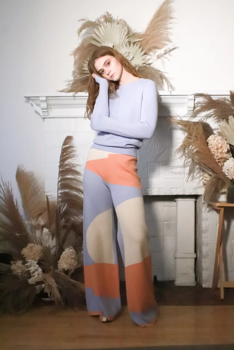 Woman weariing a desert inspired print wide leg knit lounge pants with the matching blue crewneck long sleeve. 
