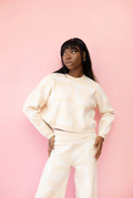 Model wearing a tan and ivory, checkered shell print cropped crewneck sweater with the matching wide leg knit lounge pants