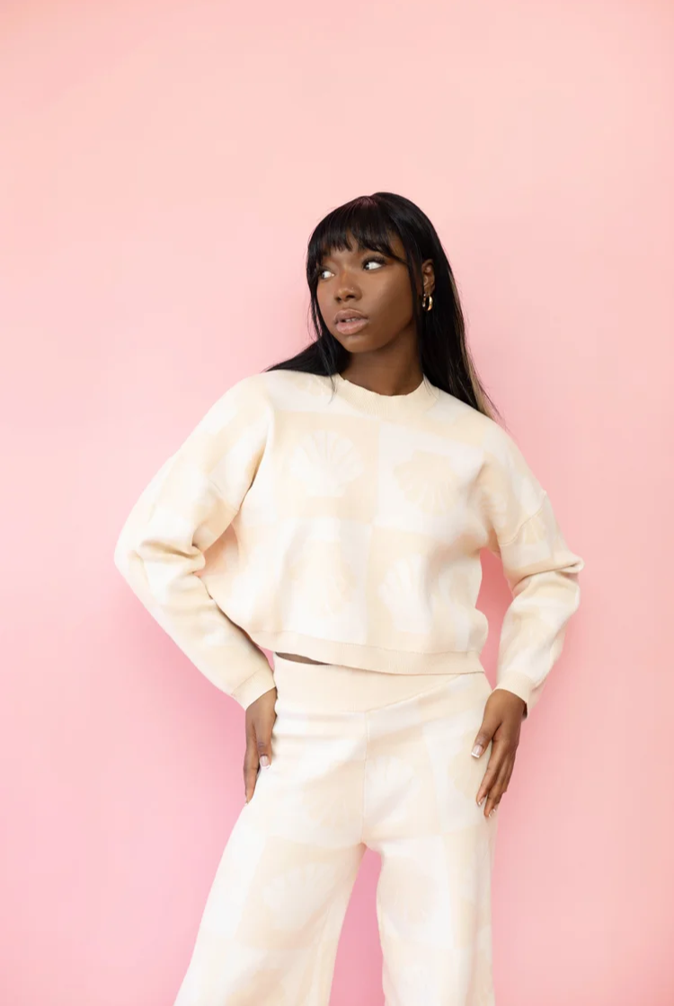 Model wearing a tan and ivory, checkered shell print cropped crewneck sweater with the matching wide leg knit lounge pants