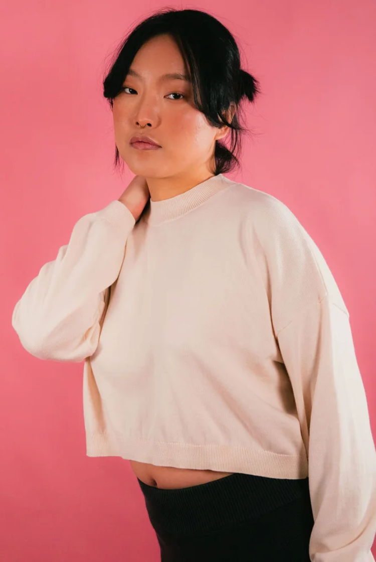 Woman wearing an ivory cropped crewneck sweater.