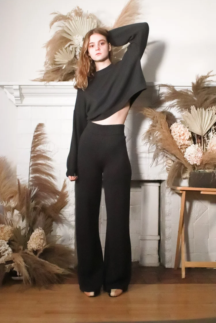 Model wearing a charcoal grey cropped crewneck sweater with the matching wide leg knit pants. 