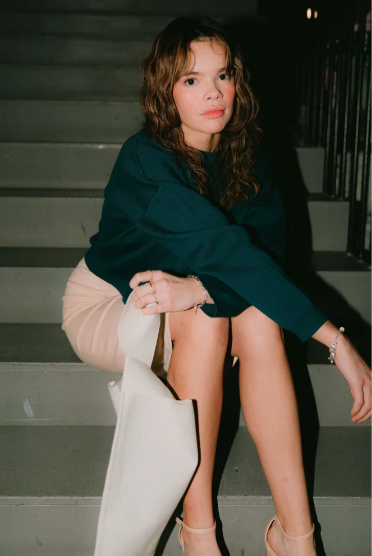 Model wearing a dark blue cropped crewneck sweater with a fitted knit midi skirt. 